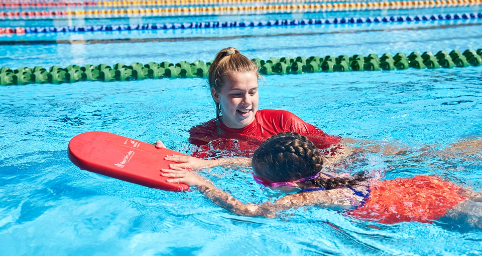 kid learning to swim by instructor